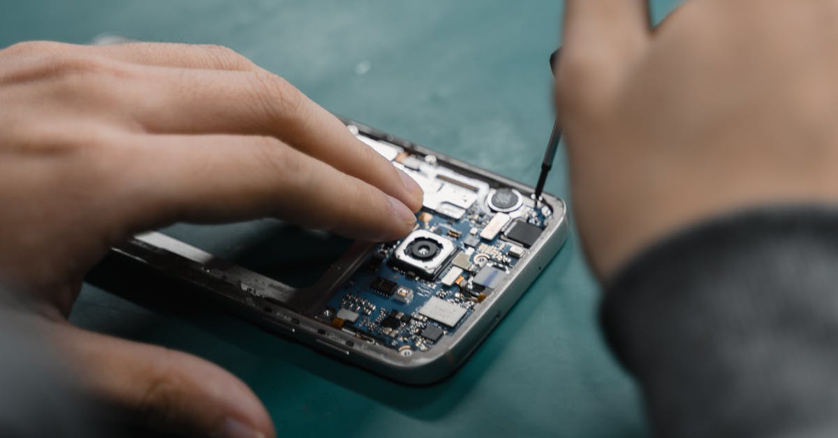 A focused view of repairing a smartphone circuit board with tools by hand.